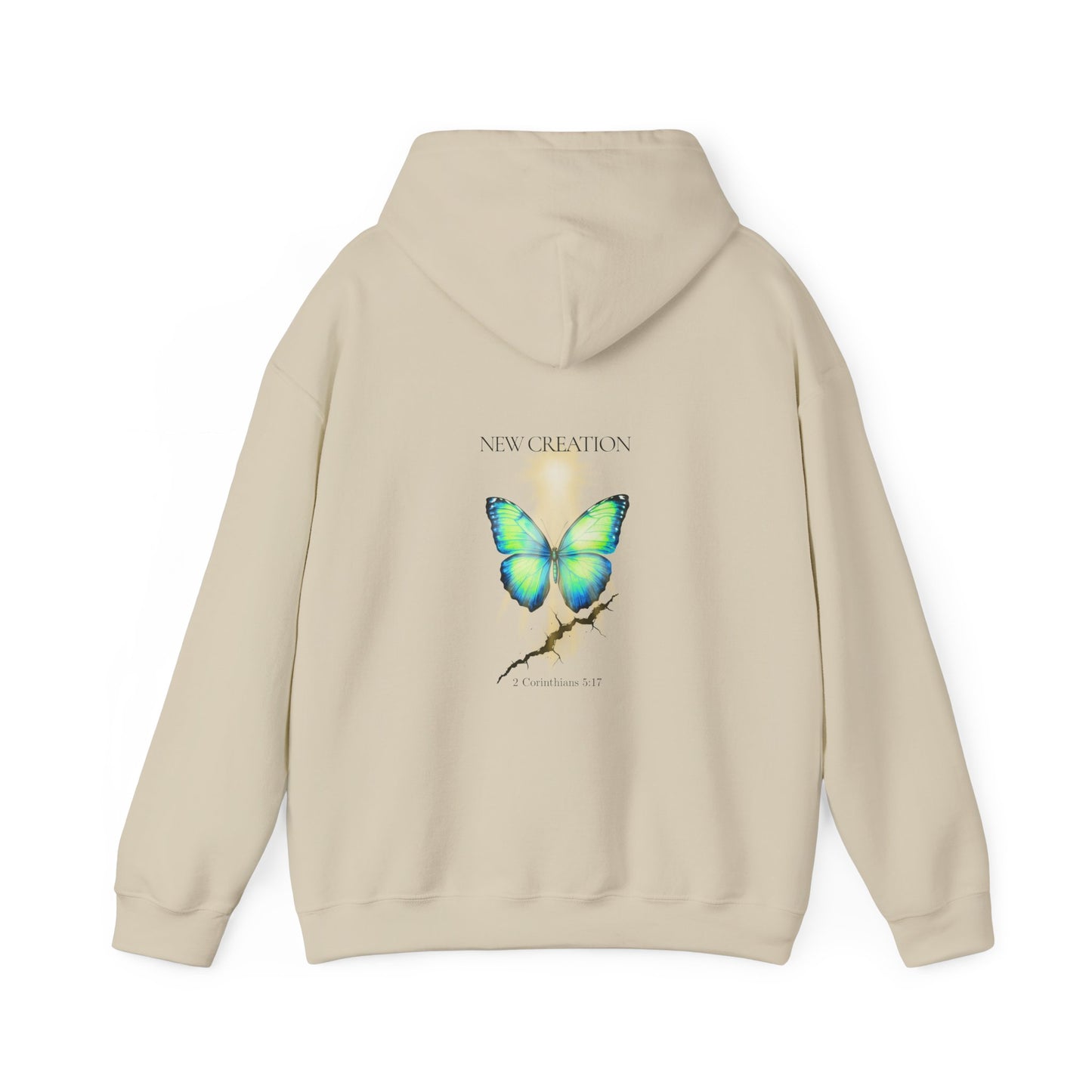 Sand Christian hoodie featuring a blue and green butterfly rising above a cracked rock, symbolizing transformation and renewal. The design includes the words 'NEW CREATION' at the top and '2 Corinthians 5:17' at the bottom, representing the Bible verse about becoming a new creation in Christ.