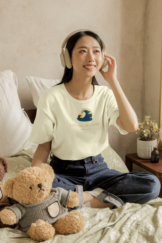 Woman sitting on a bed wearing headphones and a t-shirt with a logo, surrounded by teddy bears.